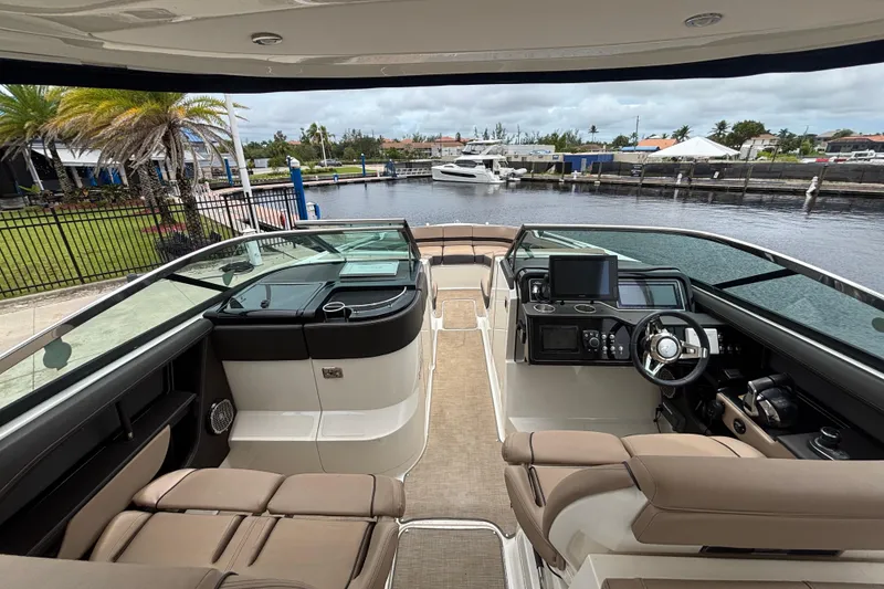 Slide: The Image of 2018 Sea Ray SLX 310 Outboard interior with helm, seating, and waterfront view. - 16
