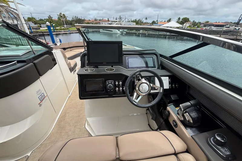 Slide: The Image of 2018 Sea Ray SLX 310 Outboard helm with modern controls and waterfront view. - 17