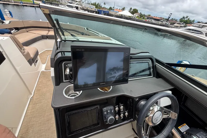 Slide: The Image of 2018 Sea Ray SLX 310 Outboard helm with Garmin GPS, steering wheel, and cup holder. - 19