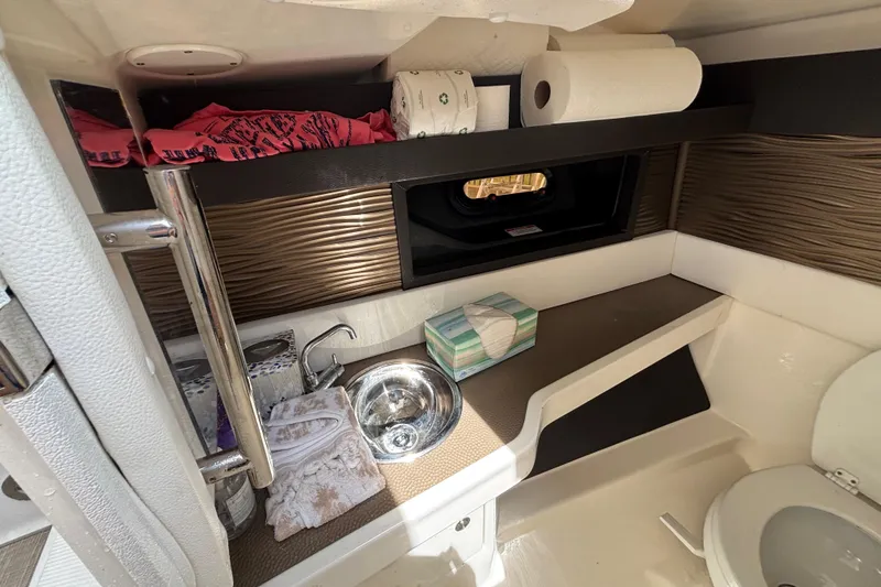 Slide: The Image of 2018 Sea Ray SLX 310 Outboard bathroom with sink, towels, and storage shelves. - 45