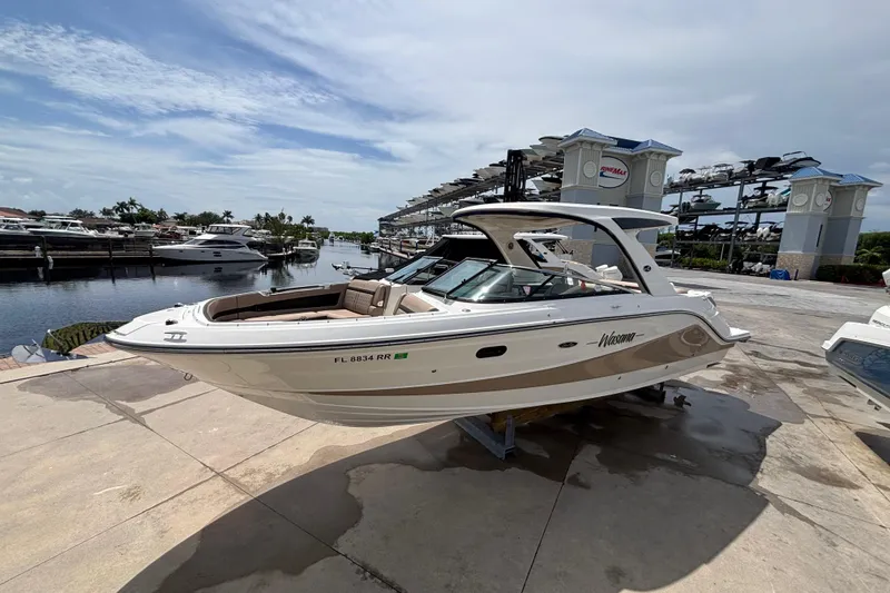 Slide: The Image of 2018 Sea Ray SLX 310 Outboard boat docked at a marina under a clear sky. - 5