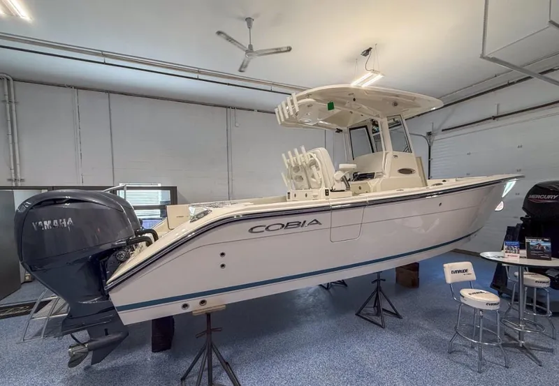 The Image of 2025 Cobia 265 Open Center Console boat displayed indoors with Yamaha engine. - 0