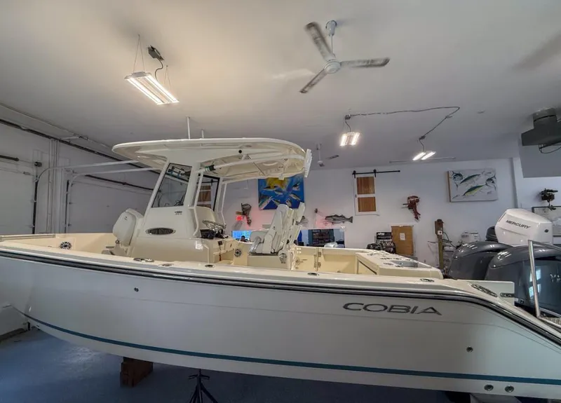 Slide: The Image of 2025 Cobia 265 Open Center Console boat in a showroom, side view. - 1