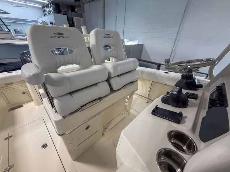 Slide: The Image of 2025 Cobia 265 Open Center Console boat interior with dual white cushioned seats and steering console. - 16