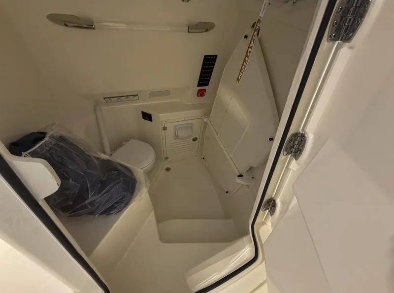 Slide: The Image of Interior of 2025 Cobia 265 Open Center Console boat, featuring compact restroom facilities. - 7