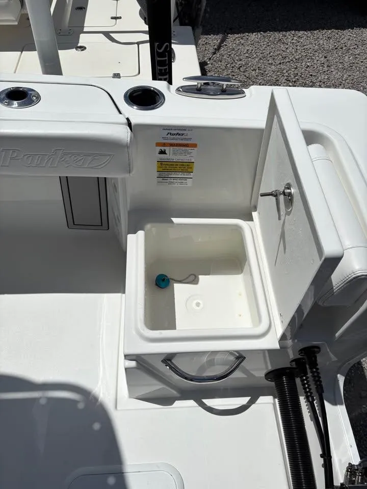 Slide: The Image of 2026 Parker 210 COASTAL boat interior with open storage compartment and cup holders. - 10