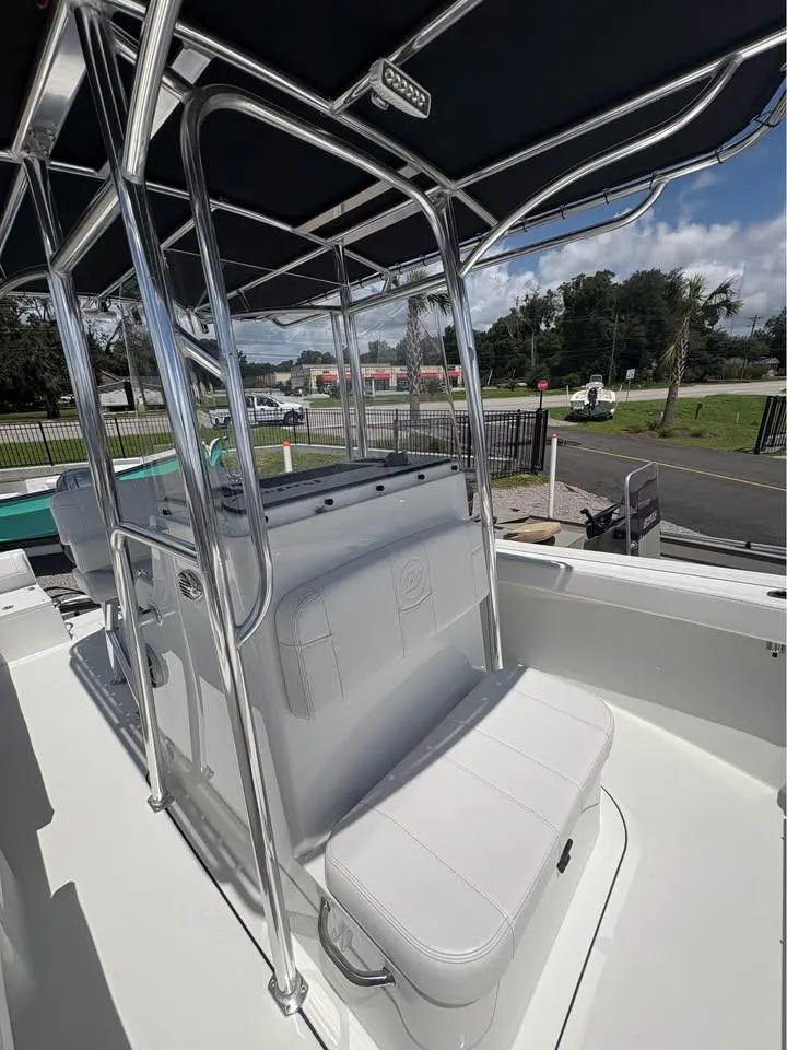 Slide: The Image of 2026 Parker 210 COASTAL boat interior with seating and canopy, parked outdoors. - 16
