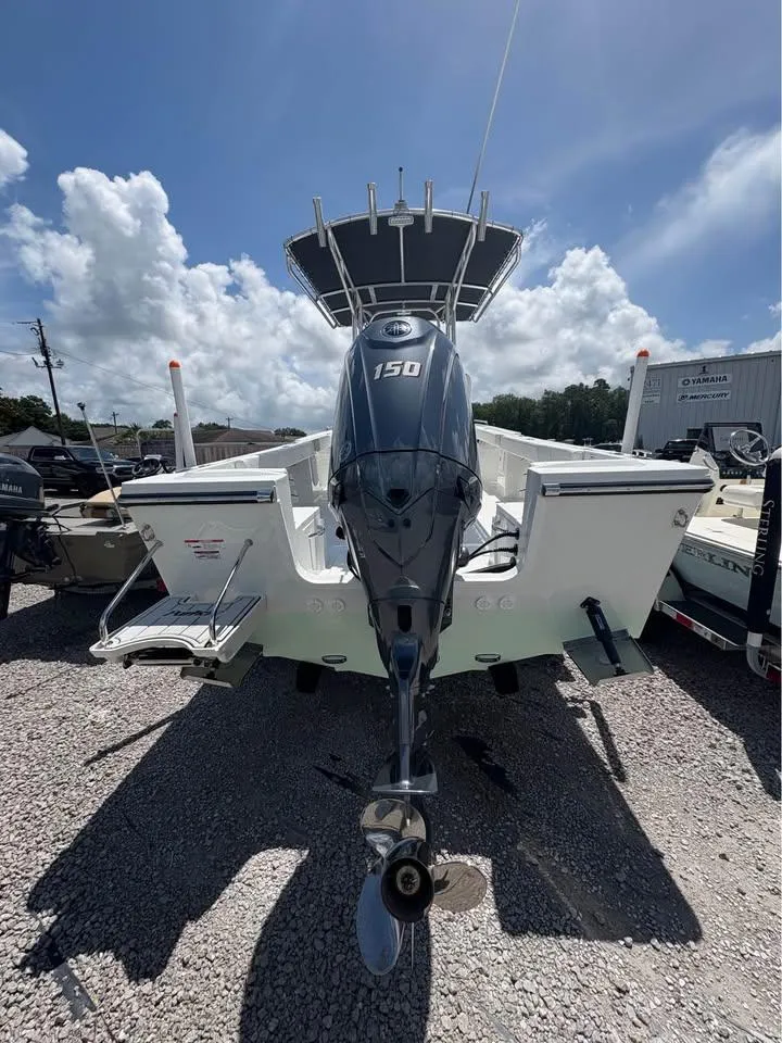 Slide: The Image of 2026 Parker 210 COASTAL boat with 150 HP engine, parked on gravel under a cloudy sky. - 3