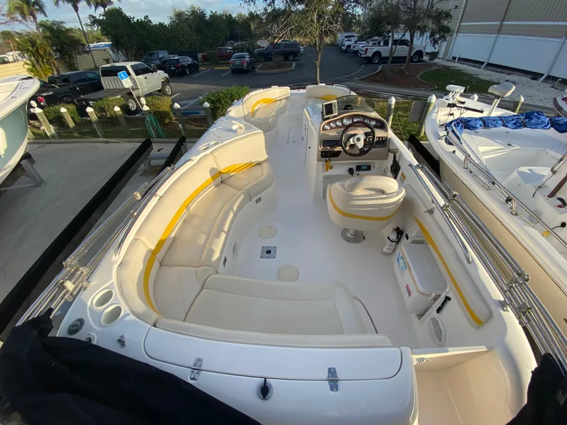 Slide: The Image of 2001 Chaparral Sunesta 232 boat interior with white and yellow seating, steering console, and parking lot view. - 10