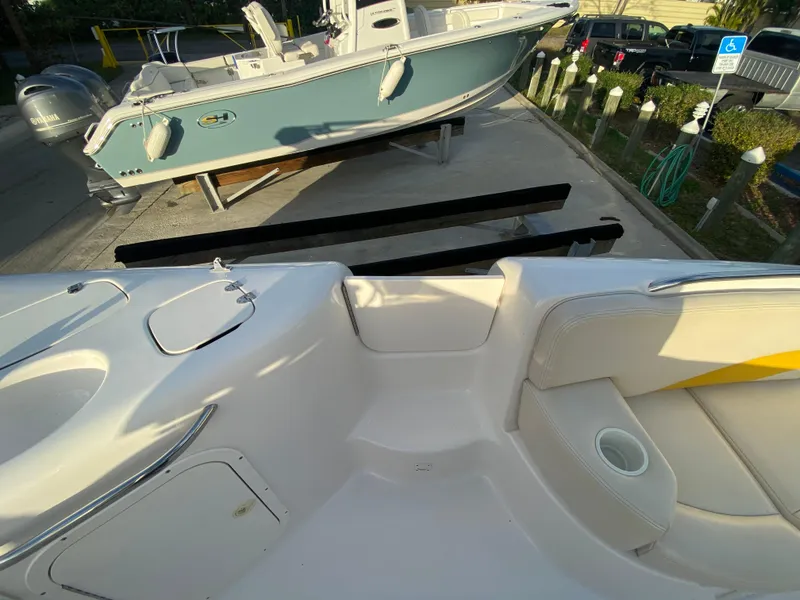 Slide: The Image of 2001 Chaparral Sunesta 232 boat interior with seating and cup holder, docked near another boat. - 14