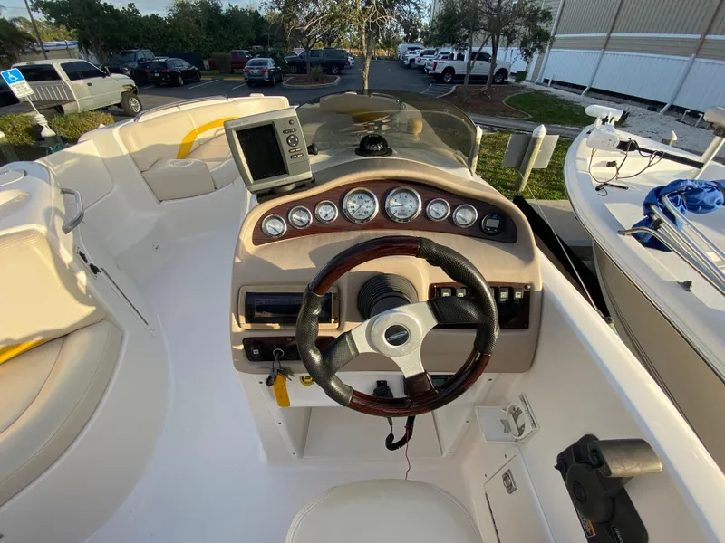 Slide: The Image of 2001 Chaparral Sunesta 232 boat dashboard with steering wheel and gauges in a marina setting. - 18