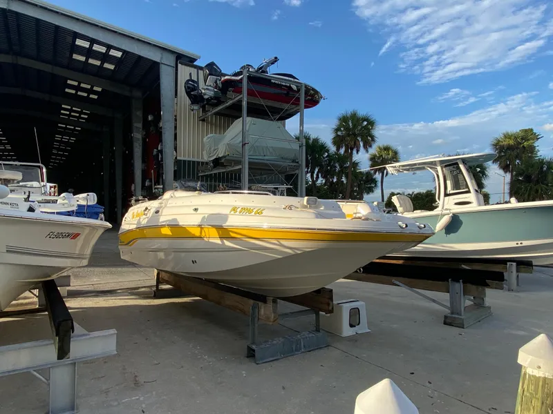 Slide: The Image of 2001 Chaparral Sunesta 232 boat on dry dock, surrounded by other boats, under a clear sky. - 7