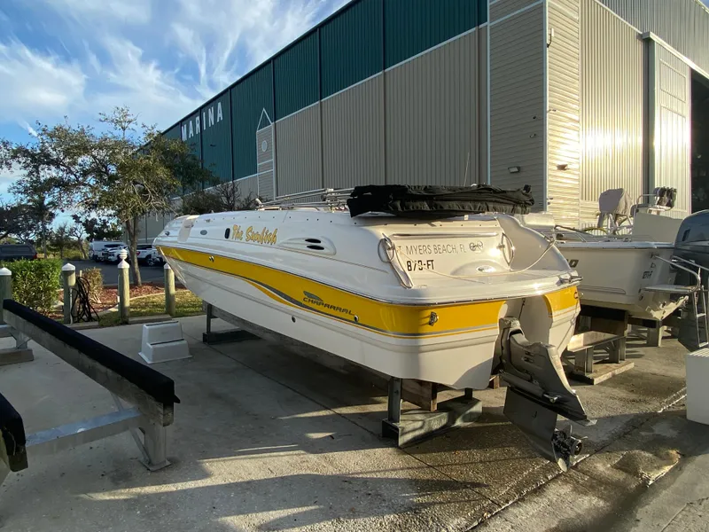 Slide: The Image of 2001 Chaparral Sunesta 232 boat with yellow stripe, docked at marina under blue sky. - 9