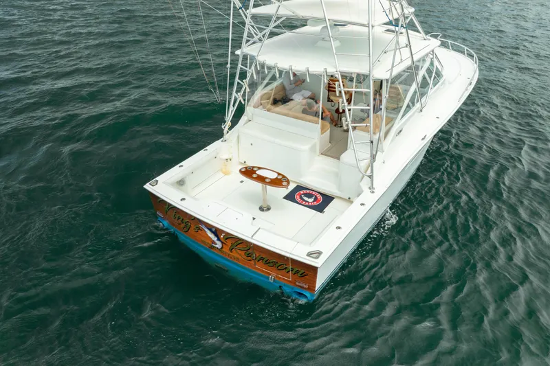 Slide: The Image of 2004 Cabo 40 Express boat on water, featuring a spacious deck and fishing equipment. - 10