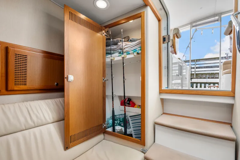 Slide: The Image of Interior of 2004 Cabo 40 Express yacht with open storage cabinet and fishing rods. - 12
