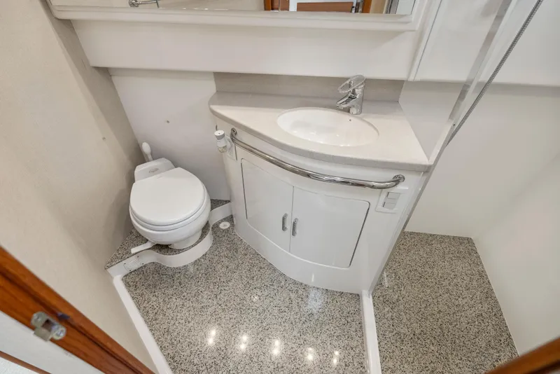Slide: The Image of 2004 Cabo 40 Express yacht bathroom with toilet, sink, and granite flooring. - 13