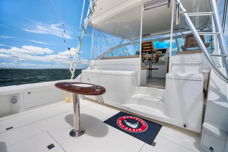 Slide: The Image of 2004 Cabo 40 Express yacht deck with seating, table, and ocean view under blue sky. - 21