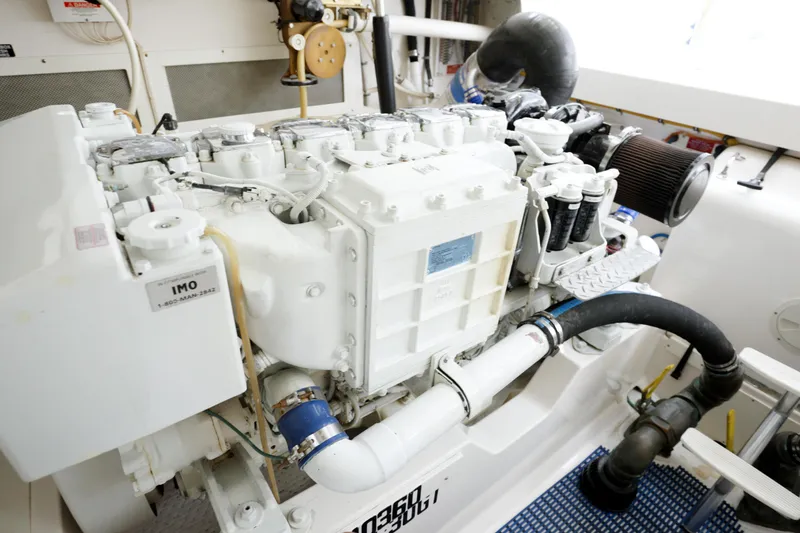 Slide: The Image of Engine room of a 2004 Cabo 40 Express boat, showcasing a clean, white engine. - 28