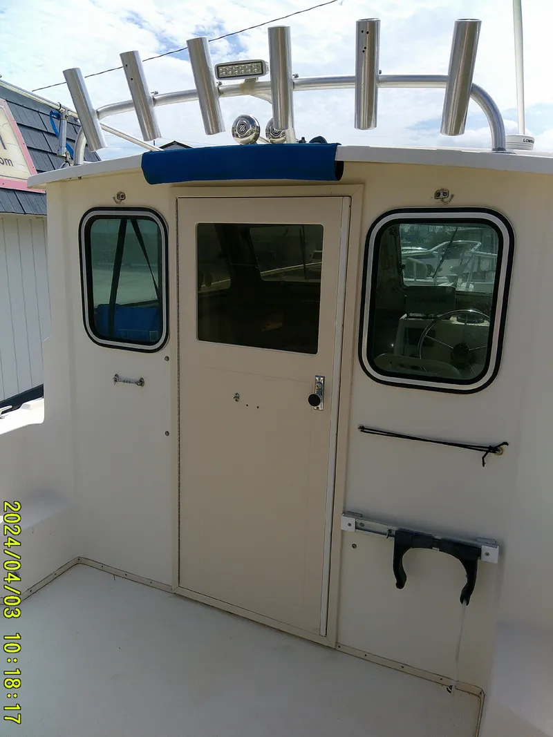 Slide: The Image of 2008 Parker 2120 Sport Cabin boat with rod holders and cabin door. - 23