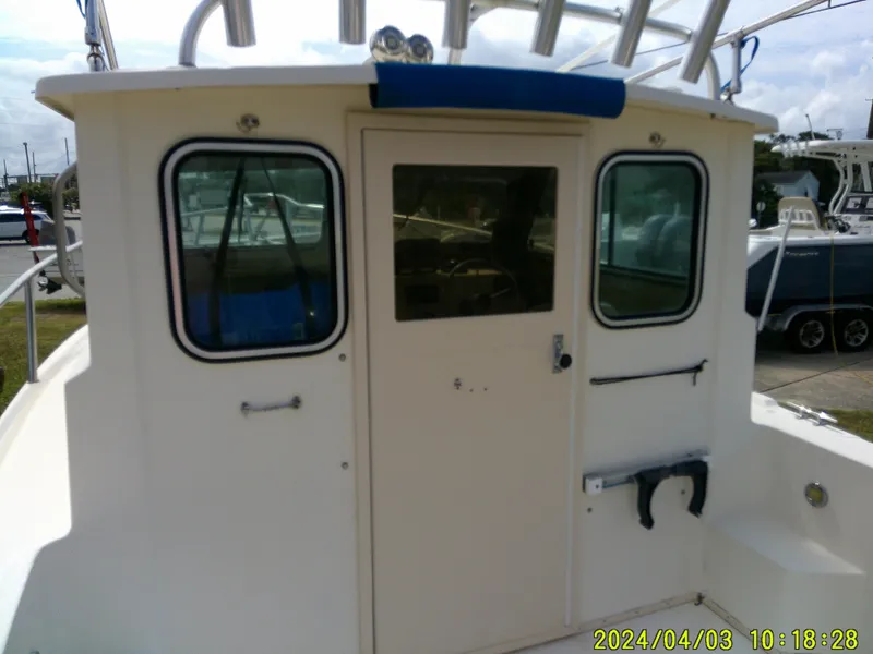 Slide: The Image of 2008 Parker 2120 Sport Cabin boat, rear view with windows and door, docked outdoors. - 25