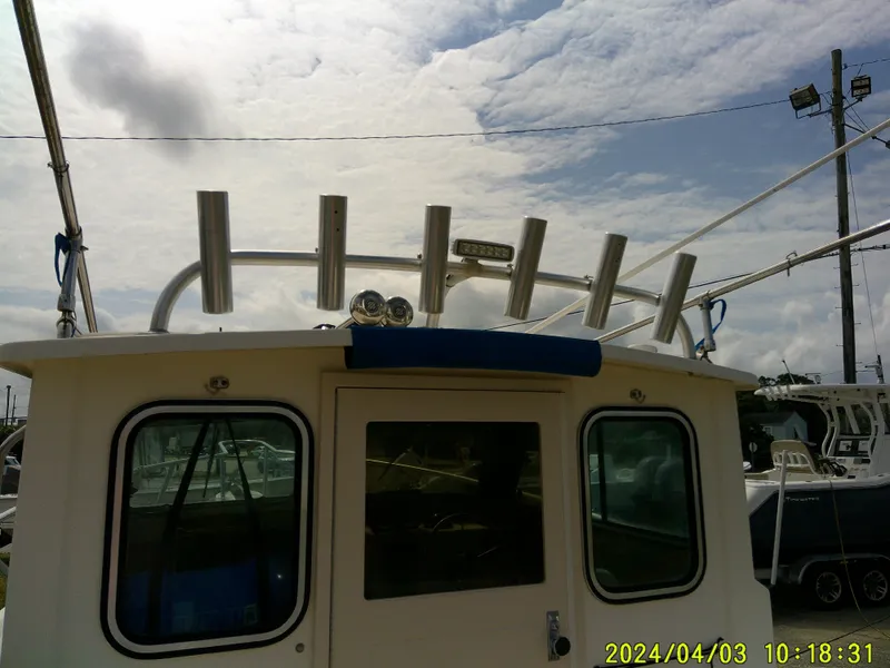 Slide: The Image of 2008 Parker 2120 Sport Cabin boat with rod holders under cloudy sky. - 26