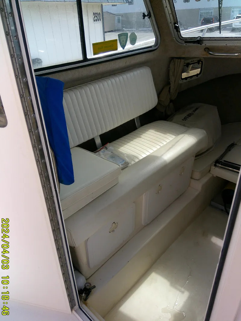 Slide: The Image of Interior of a 2008 Parker 2120 Sport Cabin boat with white seating and storage. - 28