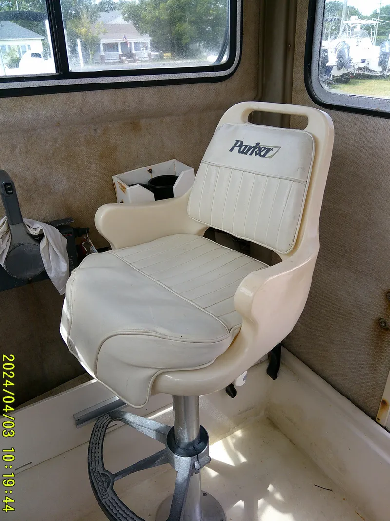Slide: The Image of Captain's chair inside 2008 Parker 2120 Sport Cabin boat, featuring white upholstery and sturdy base. - 37