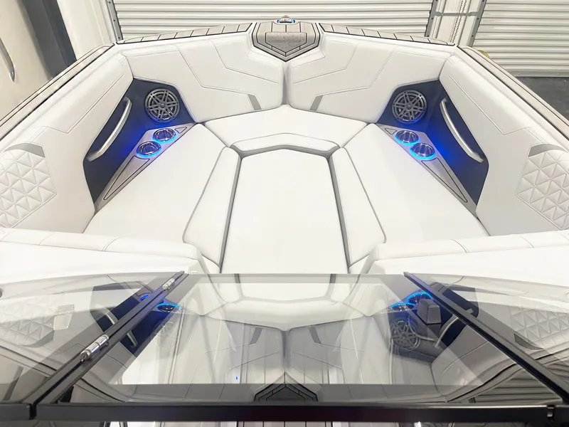 Slide: The Image of 2025 Nautique Super Air Nautique GS24 interior with white seating, blue LED cup holders, and speakers. - 13