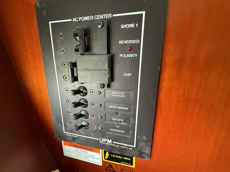 Slide: The Image of AC power center panel on a 2003 Beneteau 393 sailboat, featuring circuit breakers and warning labels. - 43