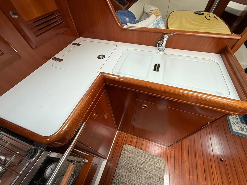 Slide: The Image of 2003 Beneteau 393 yacht kitchen with wooden cabinetry and dual sink. - 45