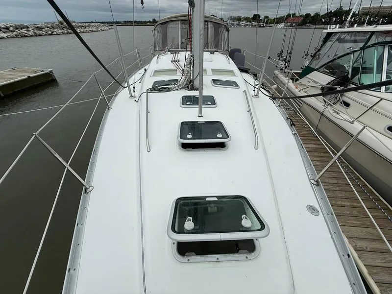 Slide: The Image of 2003 Beneteau 393 sailboat docked, showcasing deck and hatches, with marina in background. - 5