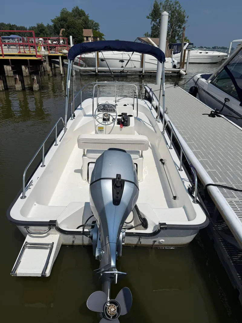 Slide: The Image of 2008 Boston Whaler 170 Montauk boat docked, featuring outboard motor and canopy. - 3