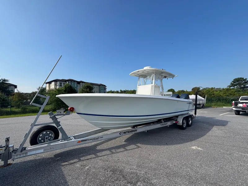 Slide: The Image of 2012 Contender 28 Sport boat on trailer in parking lot under clear blue sky. - 3