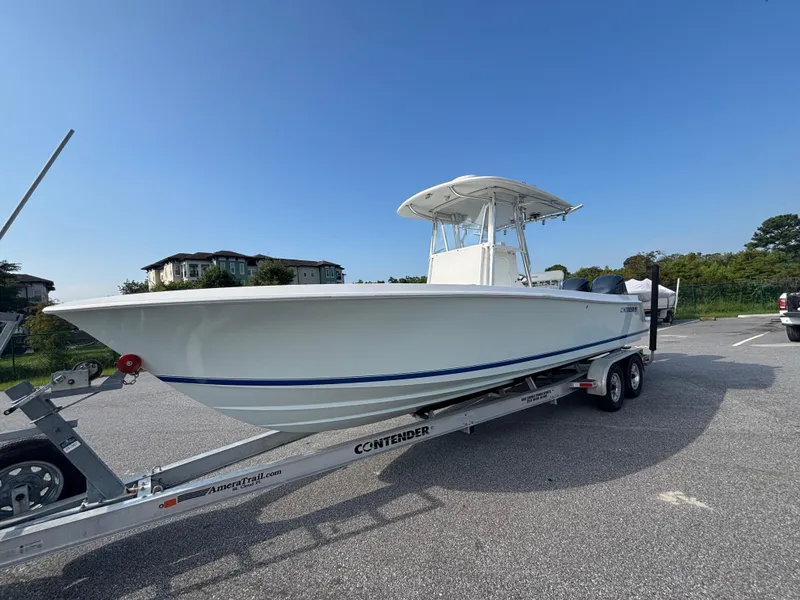 Slide: The Image of 2012 Contender 28 Sport boat on trailer in parking lot under clear blue sky. - 4