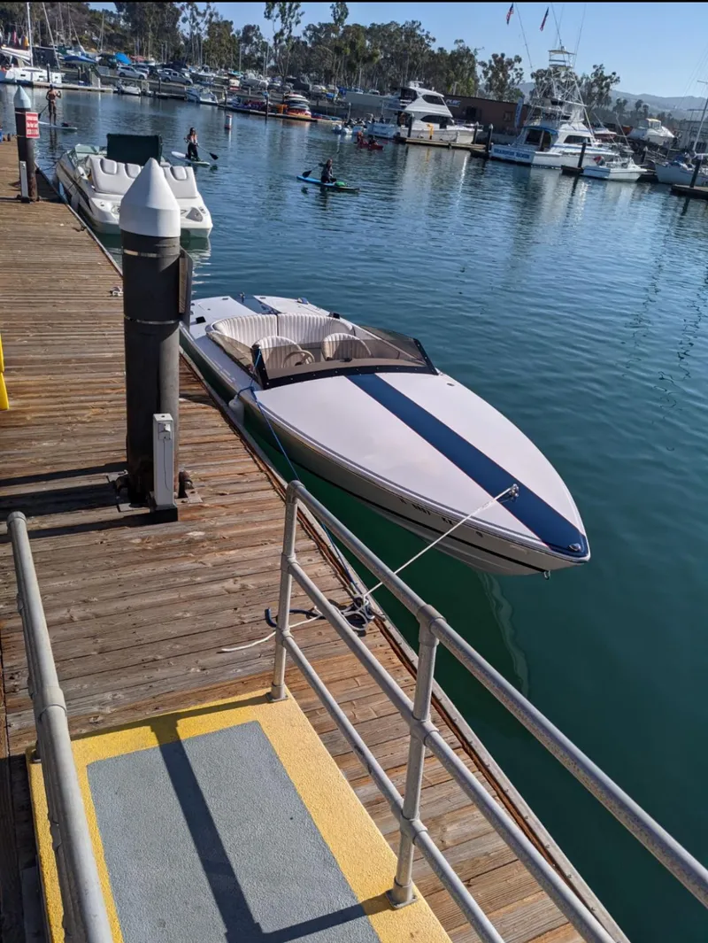 The Image of 2005 Donzi speedboat docked at a marina with calm waters and surrounding boats. - 0