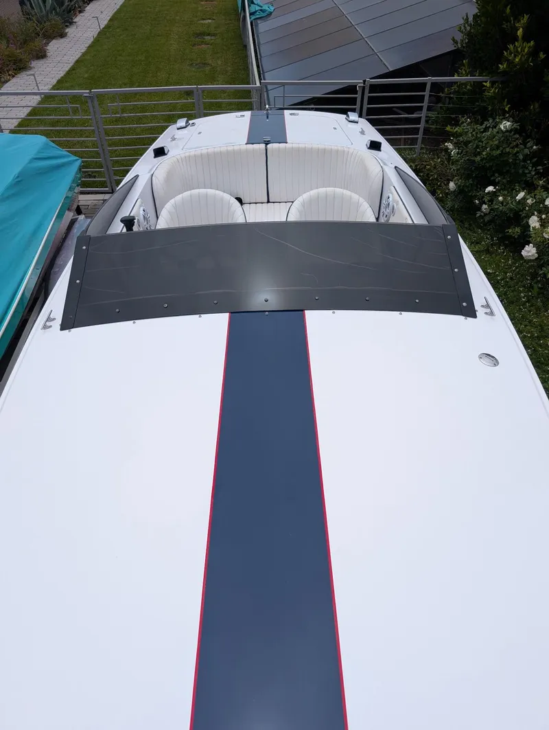 Slide: The Image of 2005 Donzi boat with sleek design, white seating, and dark stripe, docked outdoors. - 16