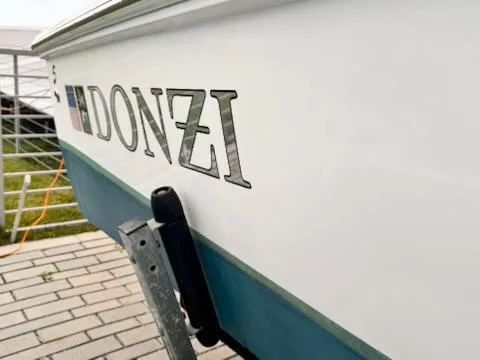 Slide: The Image of 2005 Donzi boat side view with logo, docked on brick pavement. - 21