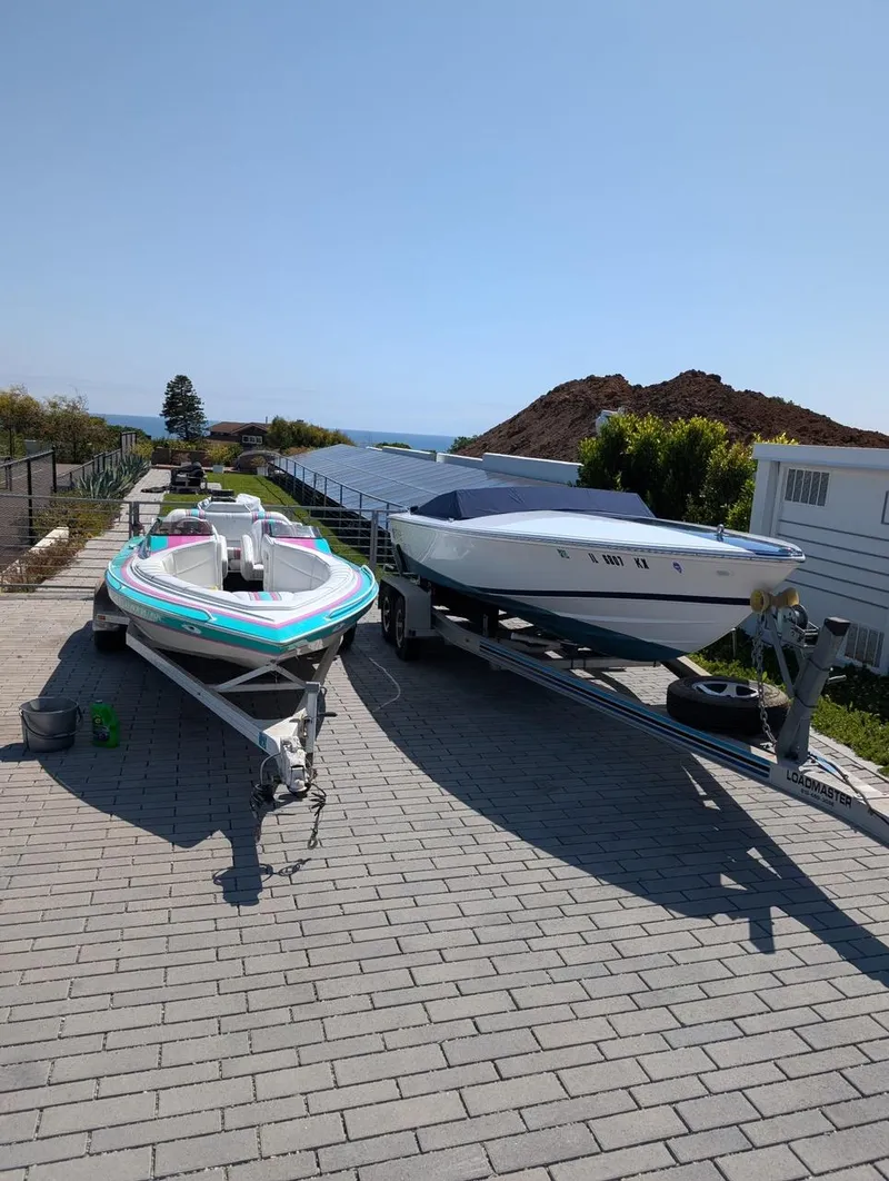 Slide: The Image of Two Donzi boats on trailers, parked on a paved driveway, with a scenic ocean view. - 24