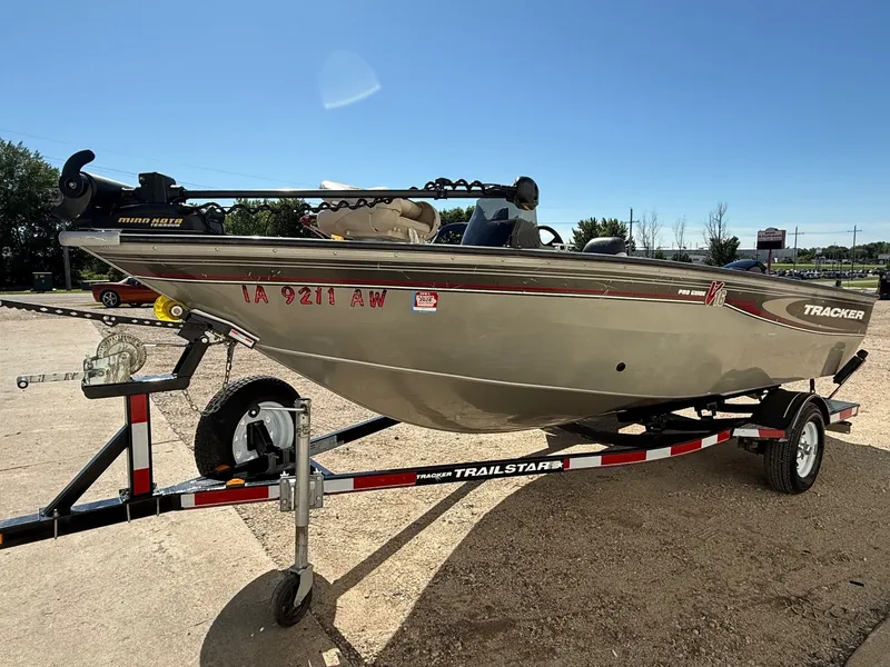 Slide: The Image of 2005 Bass Tracker PGV16 boat on a trailer, parked outdoors under clear skies. - 2