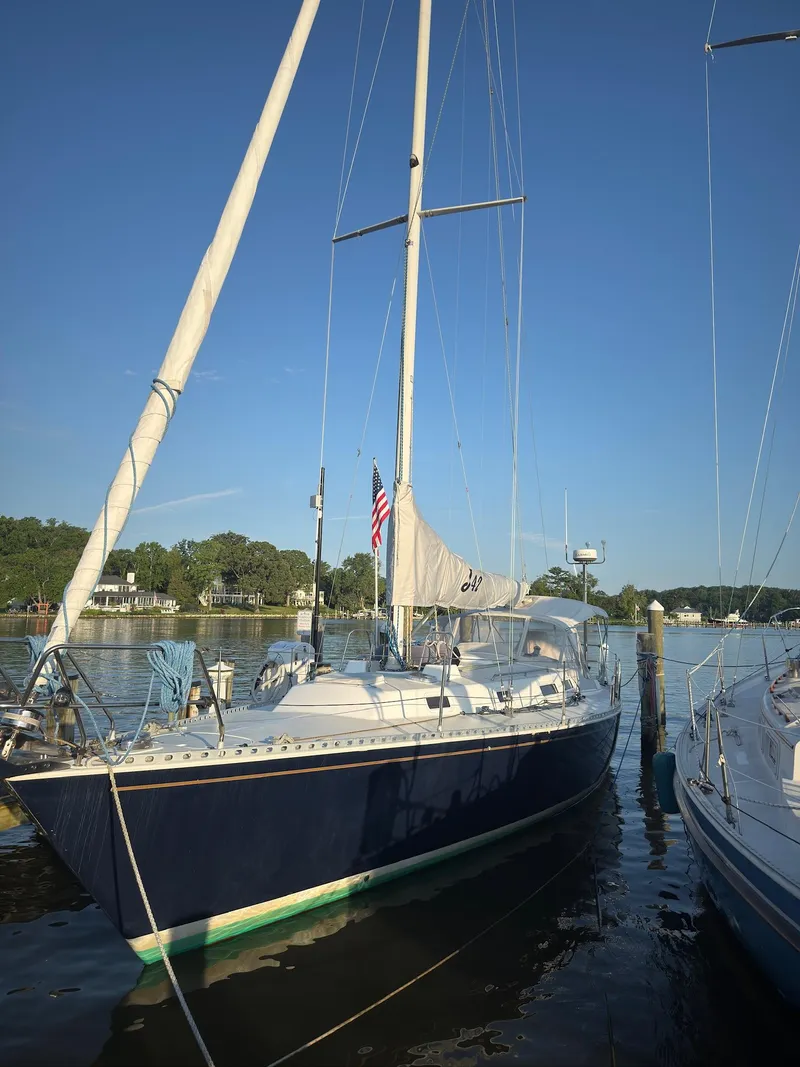 Slide: The Image of 1998 J Boats J/42 sailboat docked on a calm river under clear blue skies. - 13