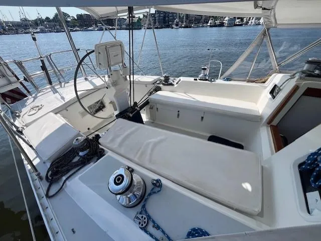 Slide: The Image of 1998 J Boats J/42 sailboat cockpit with steering wheel, winches, and seating, docked by the water. - 16