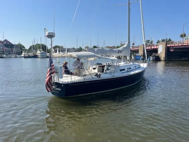 Slide: The Image of Sailboat J/42 from 1998 on calm water, featuring an American flag and marina backdrop. - 3