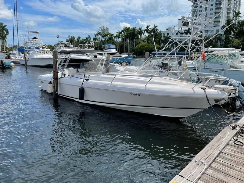 The Image of 1996 Intrepid 370 Cuddy boat docked in a marina with surrounding yachts. - 0