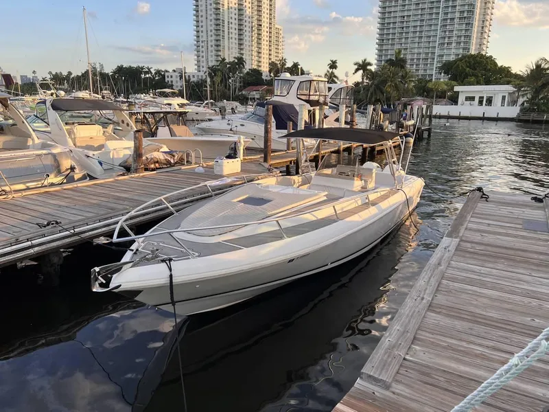 Slide: The Image of 1996 Intrepid 370 Cuddy boat docked at marina, surrounded by other vessels and high-rise buildings. - 2