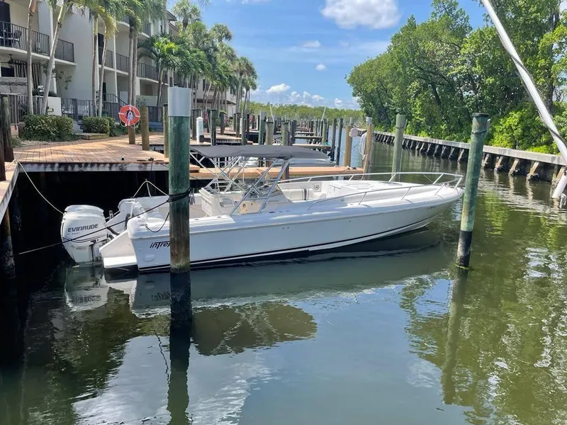 Slide: The Image of 1996 Intrepid 370 Cuddy boat docked in a serene marina setting. - 5