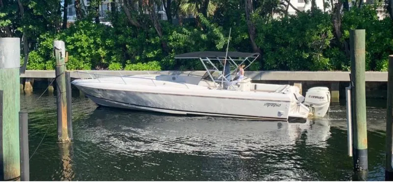 Slide: The Image of 1996 Intrepid 370 Cuddy boat cruising near a dock with lush greenery. - 8