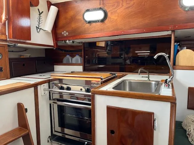 Slide: The Image of 1979 Morris Leigh 30 yacht kitchen with stove, sink, and wooden cabinetry. - 3
