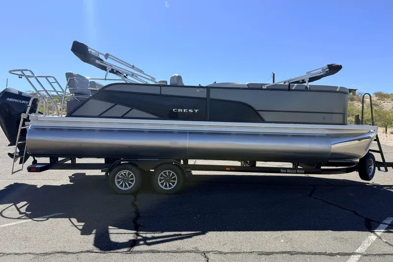 The Image of 2024 Crest Classic DLX 240 SLRC pontoon boat on trailer, parked outdoors. - 0