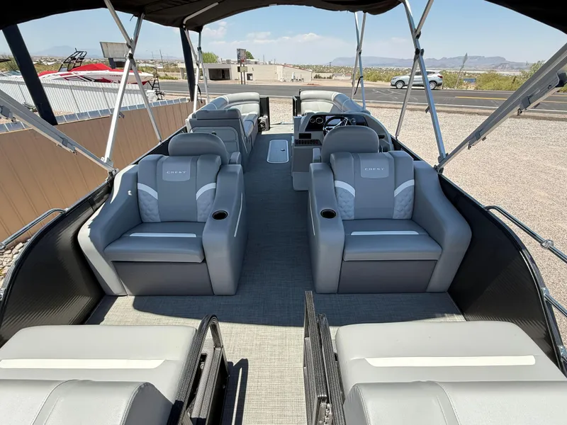 Slide: The Image of 2024 Crest Classic DLX 240 SLRC pontoon boat interior with gray seating and canopy. - 6