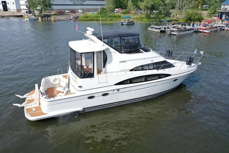 Slide: The Image of 2003 Carver 444 Cockpit Motor Yacht on calm water, dock and boats in background. - 11